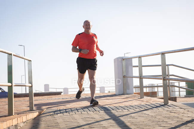 Mature senior Caucasian man working out on a promenade, running — Stock Photo