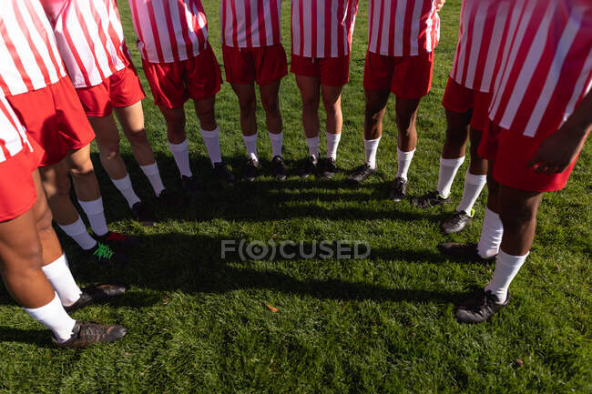Visão frontal de alto ângulo seção baixa da equipe masculina de jogadores de rugby usando sua tira de equipe, de pé no campo de jogo em um semicírculo — Fotografia de Stock