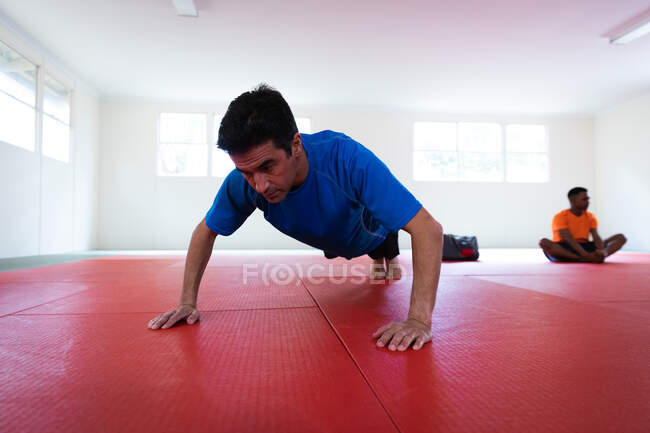Judoka haciendo flexiones en colchonetas de gimnasio - foto de stock