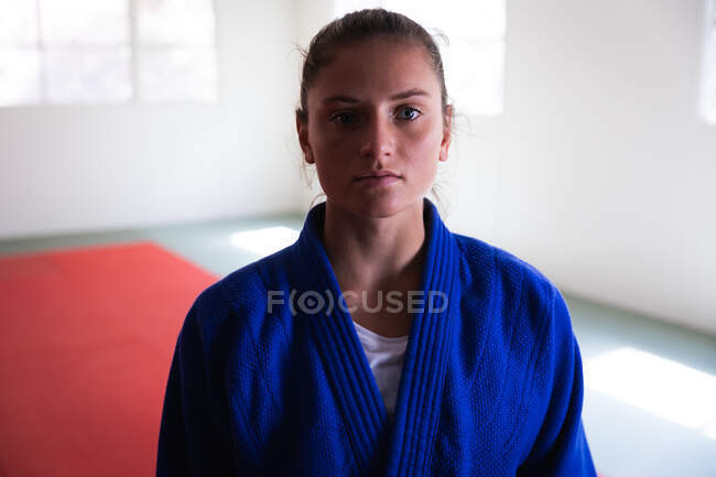 Retrato de uma adolescente confiante judoca branca vestindo judogi azul, de pé no ginásio com os braços cruzados e olhando diretamente para uma câmera. — Fotografia de Stock