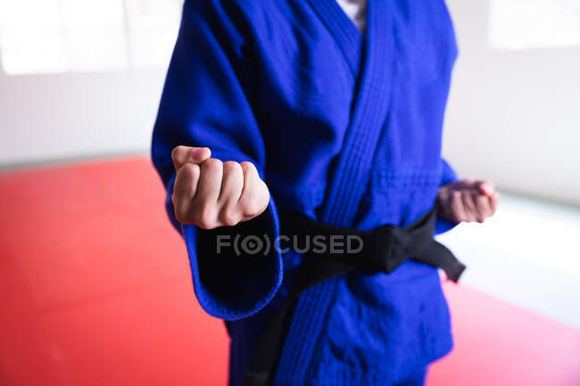 Vista frontal sección central de judoka con judogi azul, calentamiento antes de un entrenamiento en un gimnasio, golpeando una pose, golpeando el aire. - foto de stock