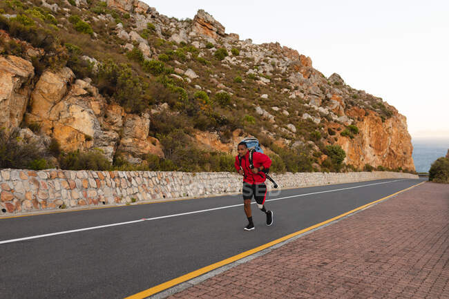 Un atleta maschio di razza mista in forma e disabile con gamba protesica, che si gode il suo tempo in gita in montagna, escursioni, passeggiate sulla strada in riva al mare. Stile di vita attivo con disabilità. — Foto stock