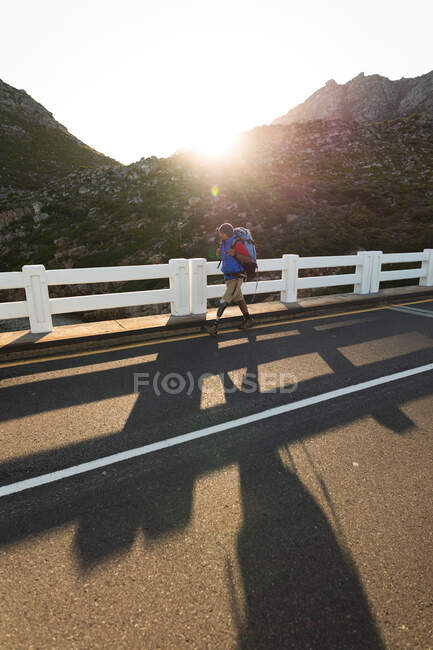 A fit, disabled mixed race male athlete with prosthetic leg, enjoying his time on a trip to the mountains, hiking, walking on the road in the mountains. Active lifestyle with disability. — Stock Photo