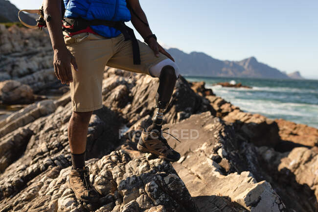 Low section of a fit, disabled male athlete with prosthetic leg, enjoying his time on a trip to the mountains, hiking, admiring the view. Active lifestyle with disability. — Stock Photo