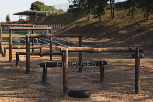 Une succession d'obstacles bas et élevés construits à partir de poteaux fixes en bois dans un camp d'entraînement par une journée ensoleillée, dans le cadre d'un parcours d'obstacles dans une salle de gym extérieure rurale — Photo de stock