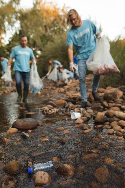 Eine multiethnische Gruppe von Naturschützern säubert Flüsse auf dem Land und sammelt Müll auf. Ökologie und soziale Verantwortung im ländlichen Raum. — Stockfoto