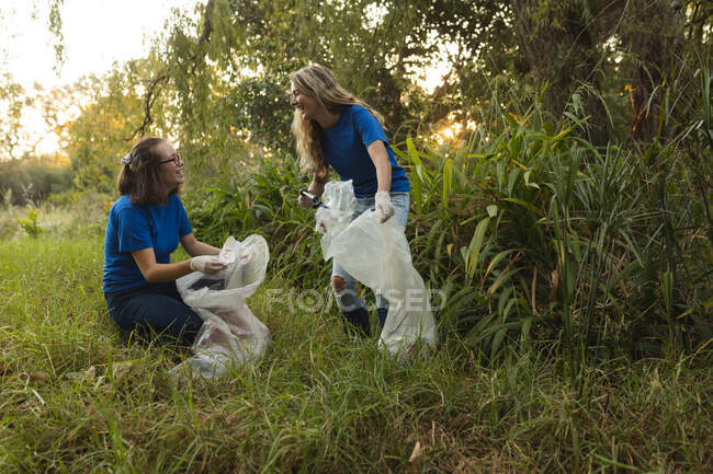 Две кавказки-волонтёры убирают лес в сельской местности, убирают мусор. Экология и социальная ответственность в сельской местности. — стоковое фото