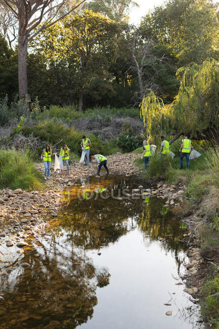 Eine multiethnische Gruppe von Naturschützern säubert Flüsse auf dem Land und sammelt Müll auf. Ökologie und soziale Verantwortung im ländlichen Raum. — Stockfoto