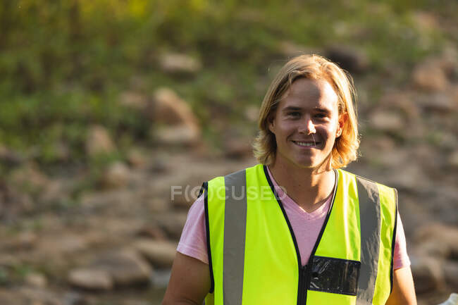 Портрет щасливого кавказького чоловіка-хранителя, який прибирає в сільській місцевості ріку, посміхається до фотоапарата. Екологія і соціальна відповідальність в сільському середовищі. — стокове фото