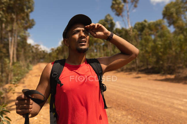 Um atleta masculino de raça mista, apto, com perna protética, aproveitando seu tempo em uma viagem, caminhadas, de pé em uma estrada de terra em uma floresta, olhando para a frente. Estilo de vida ativo com deficiência. — Fotografia de Stock