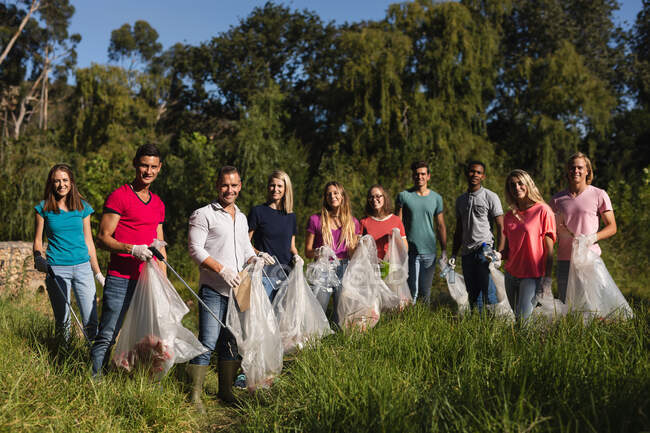 Porträt einer fröhlichen multiethnischen Gruppe von Naturschützern, die Flüsse auf dem Land säubern und Müllsäcke in der Hand halten. Ökologie und soziale Verantwortung im ländlichen Raum. — Stockfoto