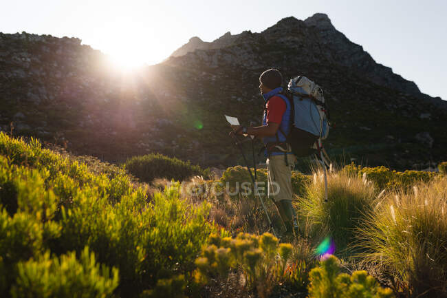 A fit, disabled mixed race male athlete with prosthetic leg, enjoying his time on a trip to the mountains, hiking, walking on the road by the sea. Active lifestyle with disability. — Stock Photo