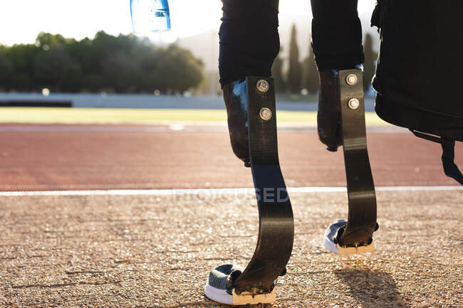 Sección baja de atleta discapacitado en un estadio de deportes al aire libre, caminando en pista de carreras con cuchillas para correr. Discapacidad atletismo entrenamiento deportivo. - foto de stock