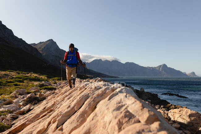 Ein fitter, behinderter Mixed-Race-Athlet mit Beinprothese, der seine Zeit bei einem Ausflug in die Berge und beim Wandern auf den Felsen am Meer genießt. Aktiver Lebensstil mit Behinderung. — Stockfoto