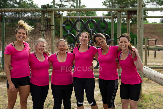 Portrait de femmes multi-ethniques portant toutes des t-shirts roses lors d'une séance d'entraînement dans un camp d'entraînement, faisant de l'exercice, posant pour une photo, souriant. Exercice de groupe en plein air, défi sain amusant. — Photo de stock
