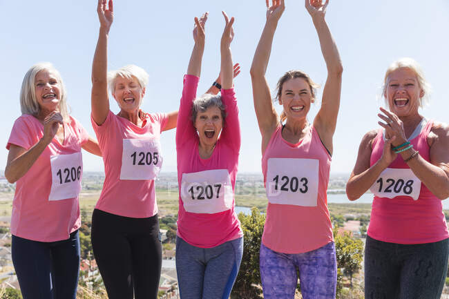 Portrait of a group of Caucasian female friends enjoying exercising on a sunny day, celebrating after running race, wearing numbers and smiling, looking at camera. — Stock Photo