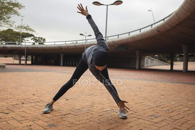 Fit gemischte Rennläuferin in Hijab und Sportbekleidung, die im Freien in der Stadt trainiert und sich im Stadtpark aufwärmt. Bewegung im städtischen Lebensstil. — Stockfoto