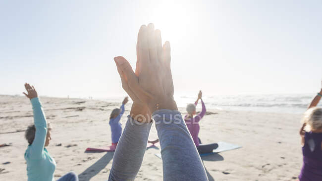Group of Caucasian female friends enjoying exercising on a beach on a sunny day, practicing yoga and sitting in yoga position. — Stock Photo