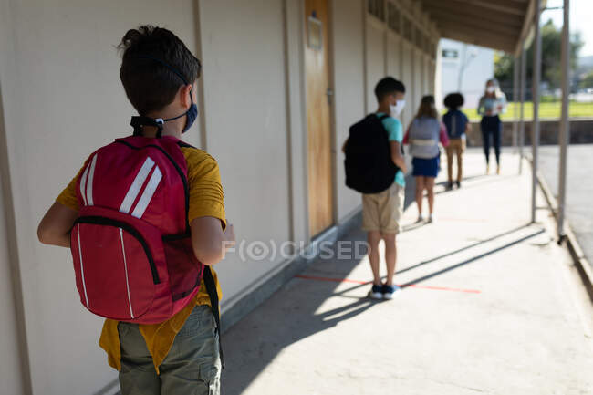 Vista posteriore di un gruppo di bambini in attesa della misura della temperatura in una scuola elementare. Istruzione primaria distanza sociale sicurezza sanitaria durante la pandemia di Covid19 Coronavirus. — Foto stock