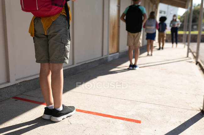 Rear view of a group of children waiting for temperature measure in an elementary school. Primary education social distancing health safety during Covid19 Coronavirus pandemic. — Stock Photo