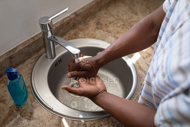 Чоловік стоїть у ванній, миє руки, соціальне дистанціювання та самоізоляцію в карантині — стокове фото