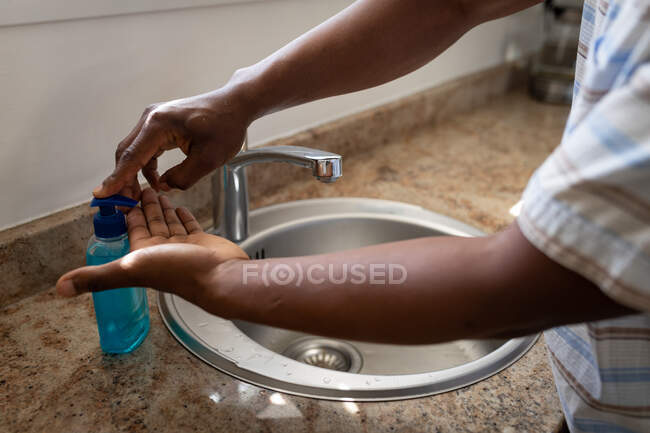 Hombre de pie en un baño, lavándose las manos, distanciamiento social y aislamiento en cuarentena - foto de stock