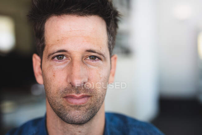 Portrait of a Caucasian man wearing casual clothes, sitting by a table in a coffee shop, looking straight into a camera — Stock Photo