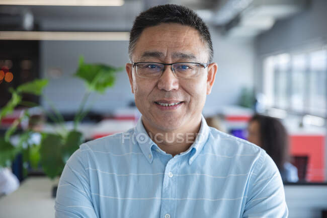 Portrait of smart casually dressed Asian male business creative wearing glasses smiling to camera. Creative business professional working in a modern office. — Stock Photo