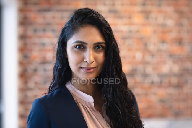 Portrait of mixed race woman working in a casual office, looking at camera. Social distancing in the workplace during Coronavirus Covid 19 pandemic. — Stock Photo