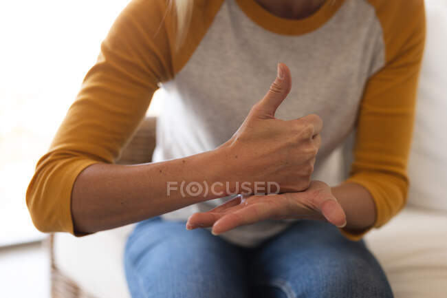 Donna trascorrere del tempo a casa, seduto su un divano, utilizzando il linguaggio dei segni. Distanza sociale durante il blocco di quarantena Covid 19 Coronavirus. — Foto stock