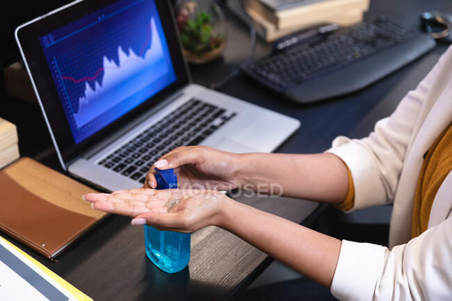 Close up of woman working in a casual office, using sanitizer. Social distancing in the workplace during Coronavirus Covid 19 pandemic. — Stock Photo