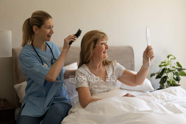 Mujer mayor caucásica en casa visitada por enfermera caucásica - foto de stock