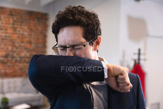 Caucasian man working in a casual office, coughing and covering his face. Social distancing in the workplace during Coronavirus Covid 19 pandemic. — Stock Photo