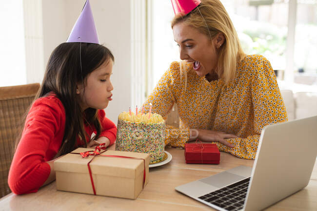 Mulher caucasiana e sua filha passam tempo em casa juntos, comemorando o aniversário, usando um computador portátil, fazendo uma chamada de vídeo. Distanciamento social durante o bloqueio de quarentena do Covid 19 Coronavirus. — Fotografia de Stock