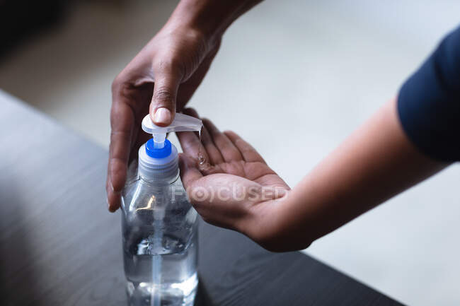 Close up of woman working in a casual office, using sanitiser. Social distancing in the workplace during Coronavirus Covid 19 pandemic. — Stock Photo