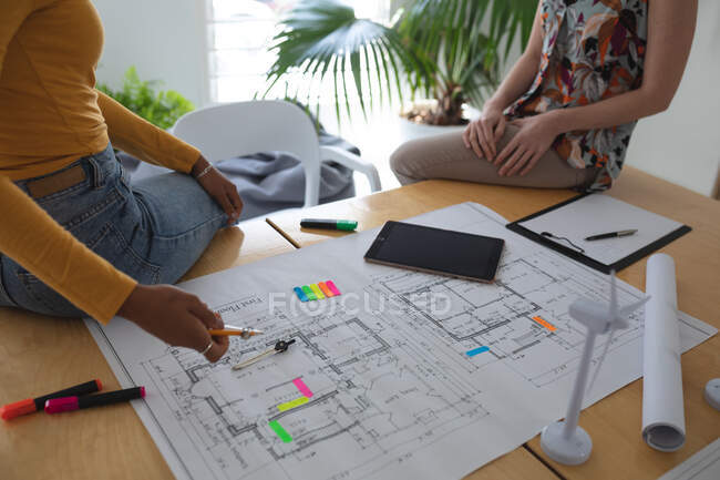 Female architects in office discussing over architectural drawing. Health and hygiene in workplace during Coronavirus Covid 19 pandemic. — Stock Photo