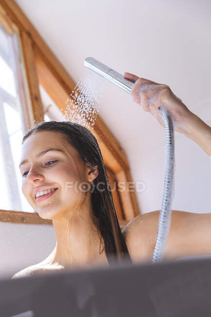 Белая женщина проводит время дома, в ванной, моет голову под душем. Социальное дистанцирование во время изоляции коронавируса Covid 19. — стоковое фото
