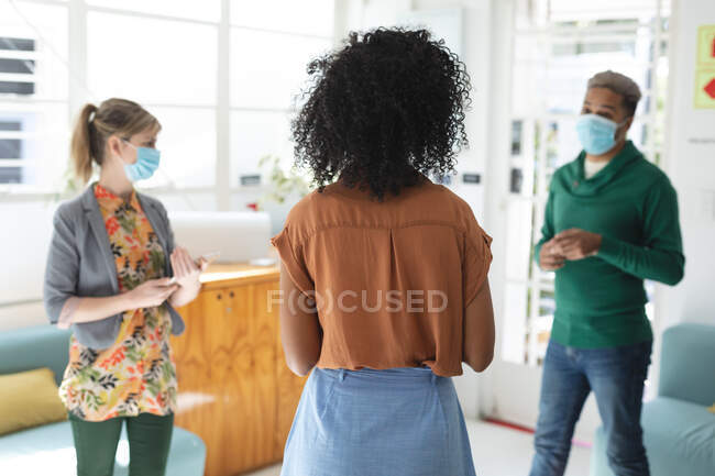 Multi ethnic group of male and female business creatives wearing face masks in office brainstorming. Health and hygiene in the workplace during Coronavirus Covid 19 pandemic. — Stock Photo