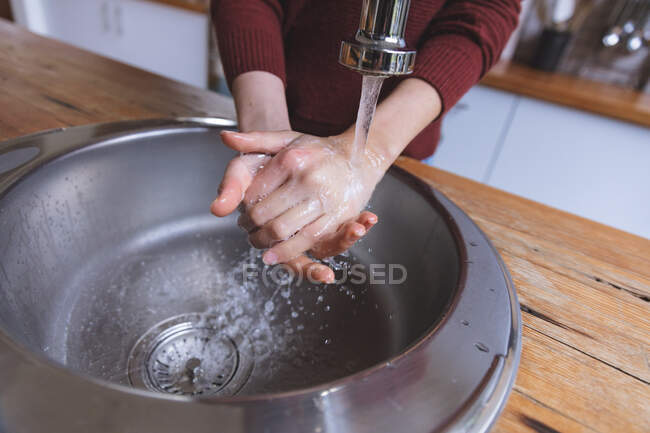 Parte média da mulher passar o tempo em casa, de pé na cozinha lavar as mãos na bacia. Distanciamento social durante o bloqueio de quarentena do Covid 19 Coronavirus. — Fotografia de Stock