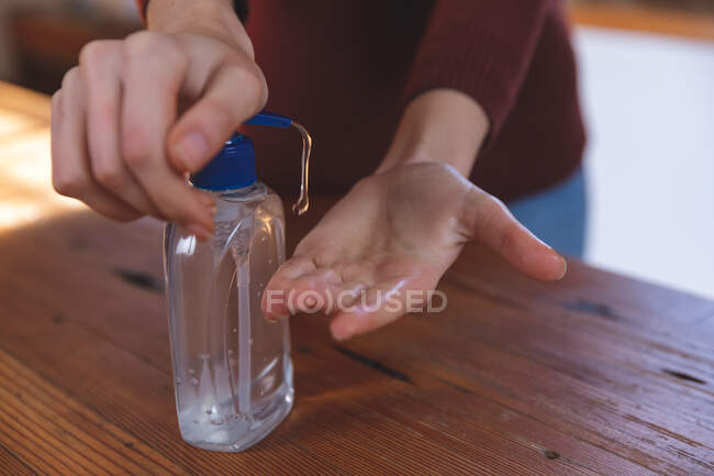 Mid section of woman spending time at home, sanitizing her hands in kitchen. Social distancing during Covid 19 Coronavirus quarantine lockdown. — Stock Photo
