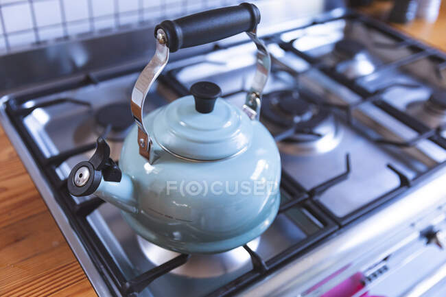 Primo piano di bollitore tradizionale blu pastello su piano cottura a gas in piano di lavoro in legno in cucina. Interni design idea cucina. — Foto stock