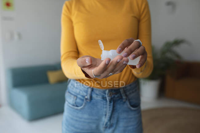 Sezione centrale della donna in piedi in ufficio disinfettando le mani con disinfettante per le mani. Salute e igiene sul luogo di lavoro durante la pandemia di Coronavirus Covid 19. — Foto stock