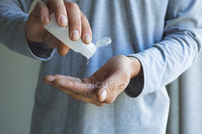 Mid section of man spending time at home, using hands sanitizer to cleanse his hands on grey background. Social distancing during Covid 19 Coronavirus quarantine lockdown. — Stock Photo