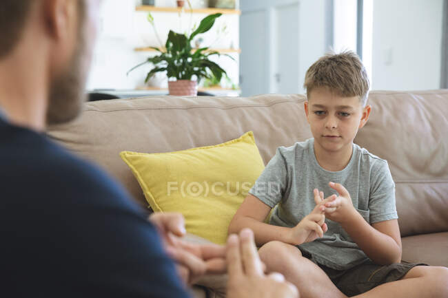 Caucasian man at home with his son together, sitting on sofa in living room, playing. Social distancing during Covid 19 Coronavirus quarantine lockdown. — Stock Photo