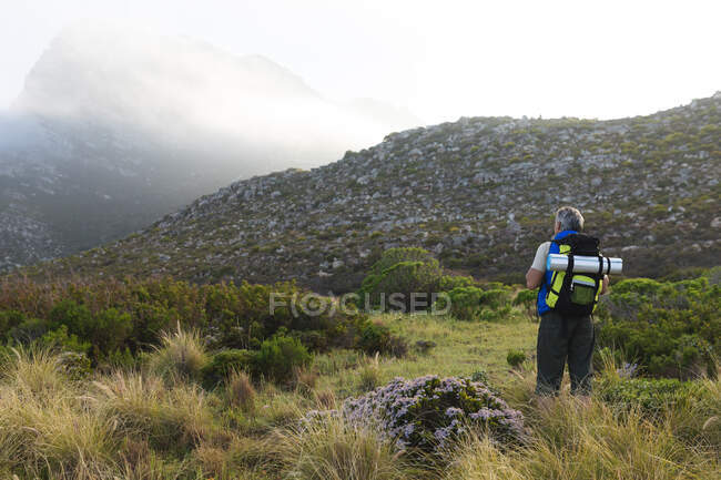 Старший чоловік проводить час в природі, ходить в гори, стоїть і насолоджується видом. здоровий спосіб життя пенсійна діяльність . — стокове фото