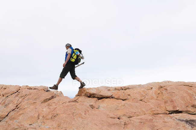 Старший чоловік проводить час у природі, гуляючи в горах, гуляючи по скелі. здоровий спосіб життя пенсійна діяльність . — стокове фото