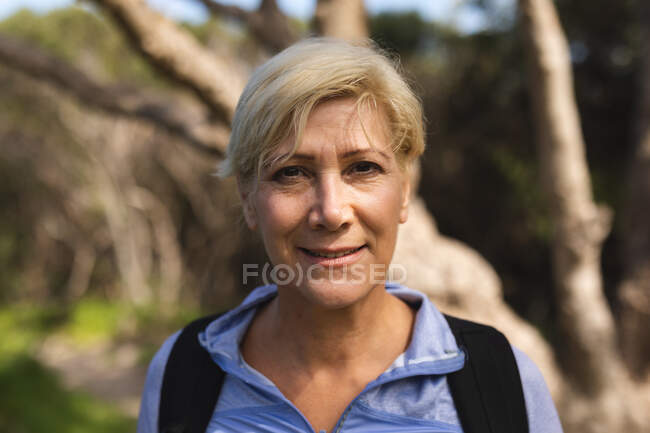Портрет старшої жінки, яка проводить час у природі, йде в гори, дивиться на камеру і посміхається. Здоровий спосіб життя. — стокове фото