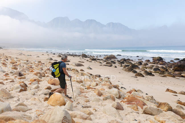 Homem sênior passando tempo na natureza, andando nas montanhas, de pé na praia, apreciando a vista. atividade de aposentadoria saudável. — Fotografia de Stock