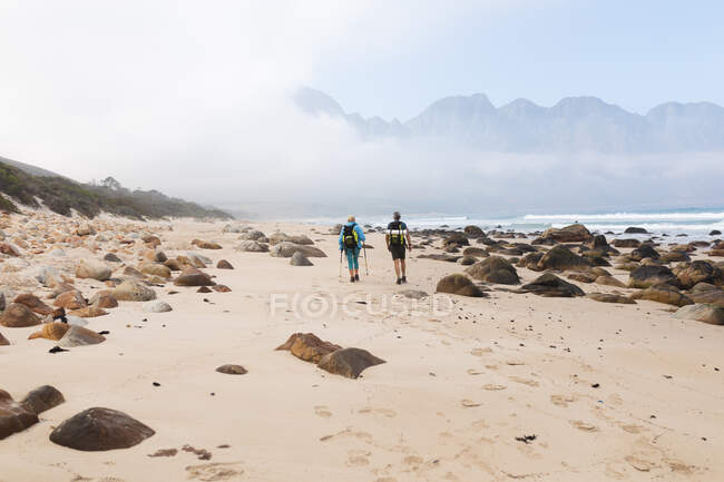 Senior couple spending time in nature together, walking on the beach. healthy lifestyle retirement activity. — Stock Photo
