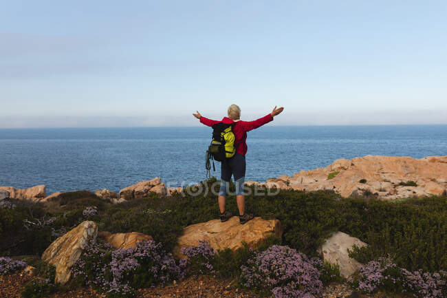 Senior woman spending time in nature, walking in the mountains, enjoying her view, spreading her arms. healthy lifestyle retirement activity. — Stock Photo